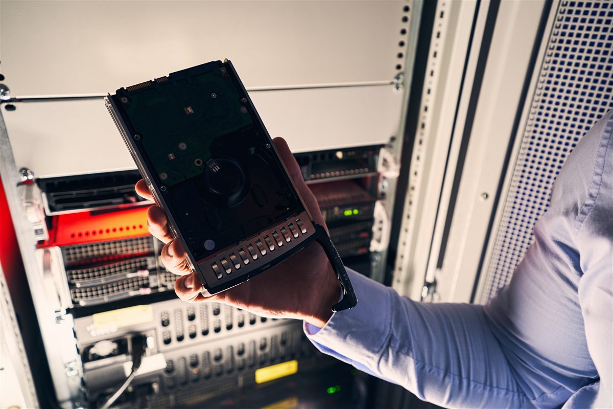 IT-Techniker mit Festplatte im Rechenzentrum – Hardware-Logistik